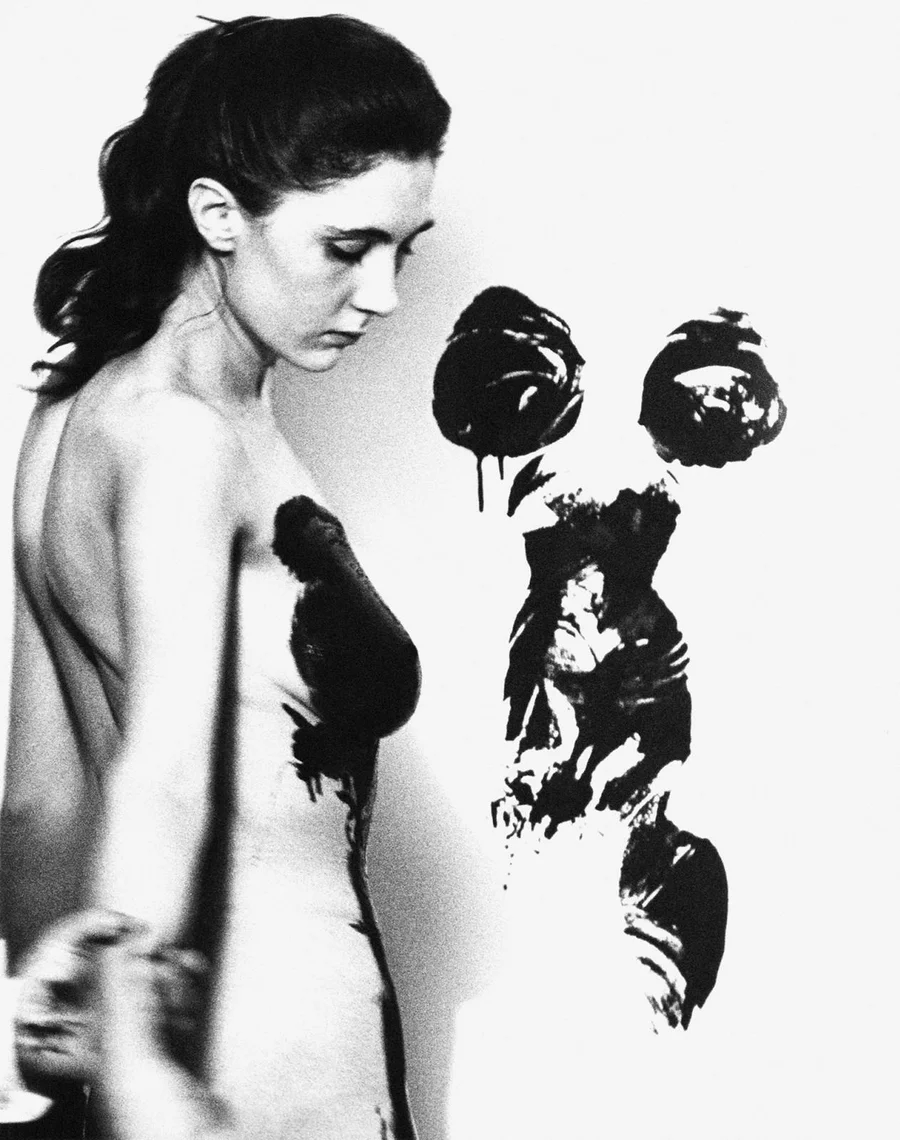Archival portrait of a model with body paint beside prints on canvas