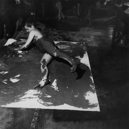 Working with paint on a canvas spread across the floor